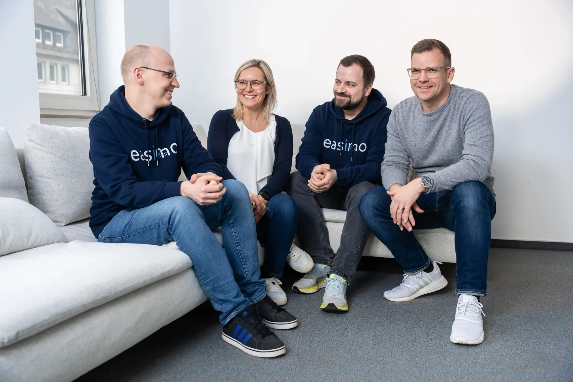 Die vier Gründer von easimo sitzen gemeinsam auf einem Sofa im Büro.