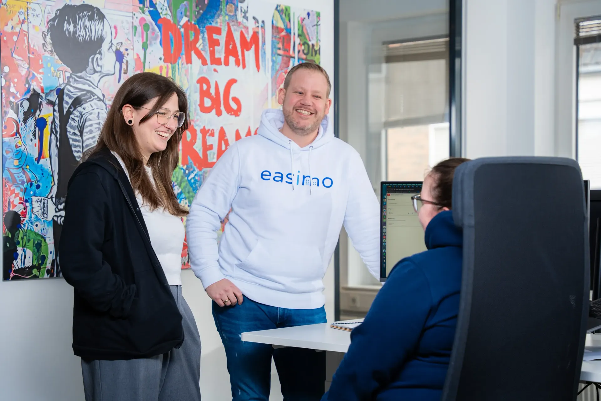 Consulting-Team von easimo im Austausch am Arbeitsplatz zur Beratung rund um Immobilienverwaltung und Softwareprozesse.