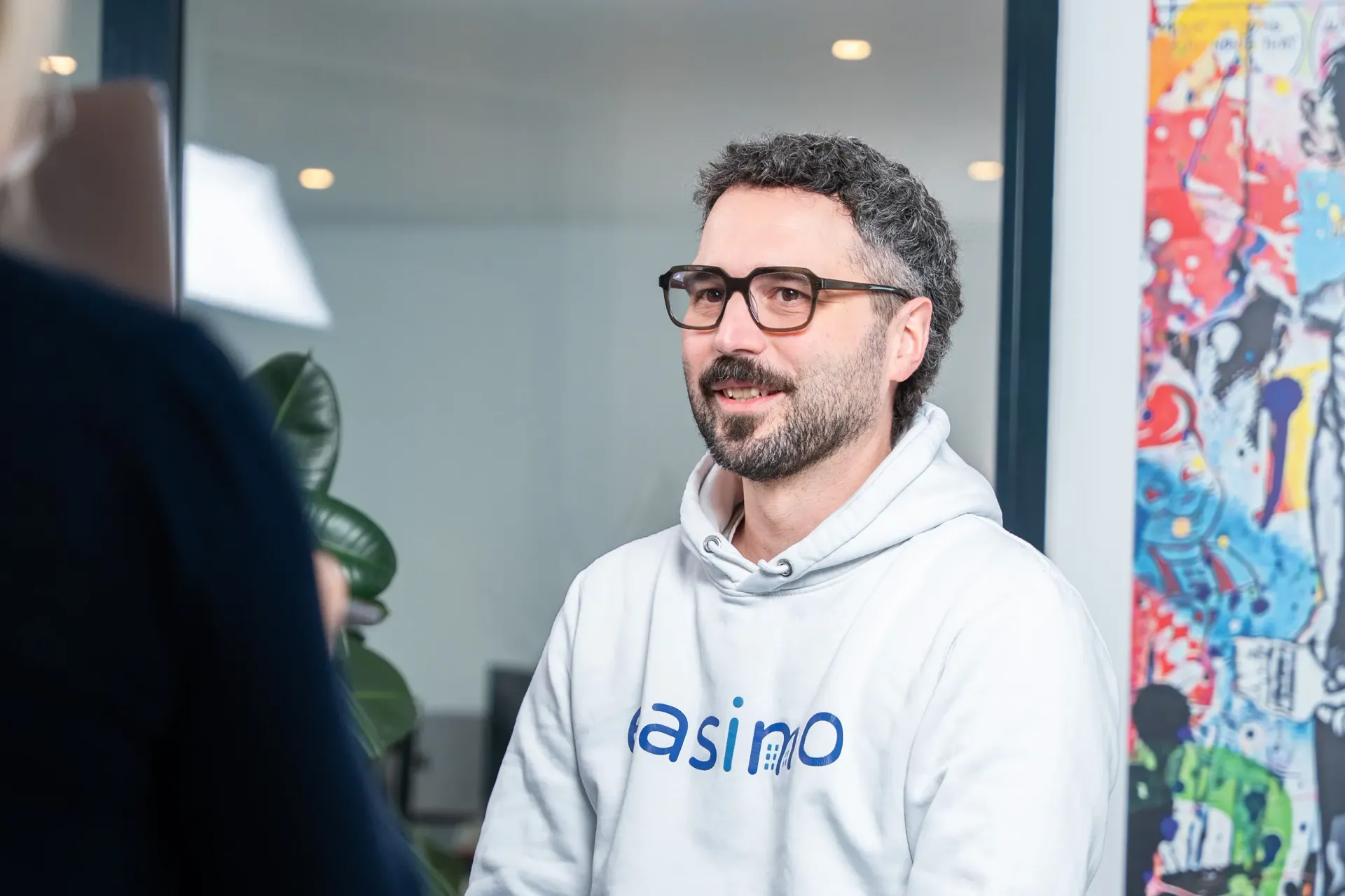Migrationsteam von easimo im Beratungsgespräch: Mitarbeiter mit easimo-Hoodie erklärt die Datenmigration für webbasierte Immobilienverwaltungssoftware.