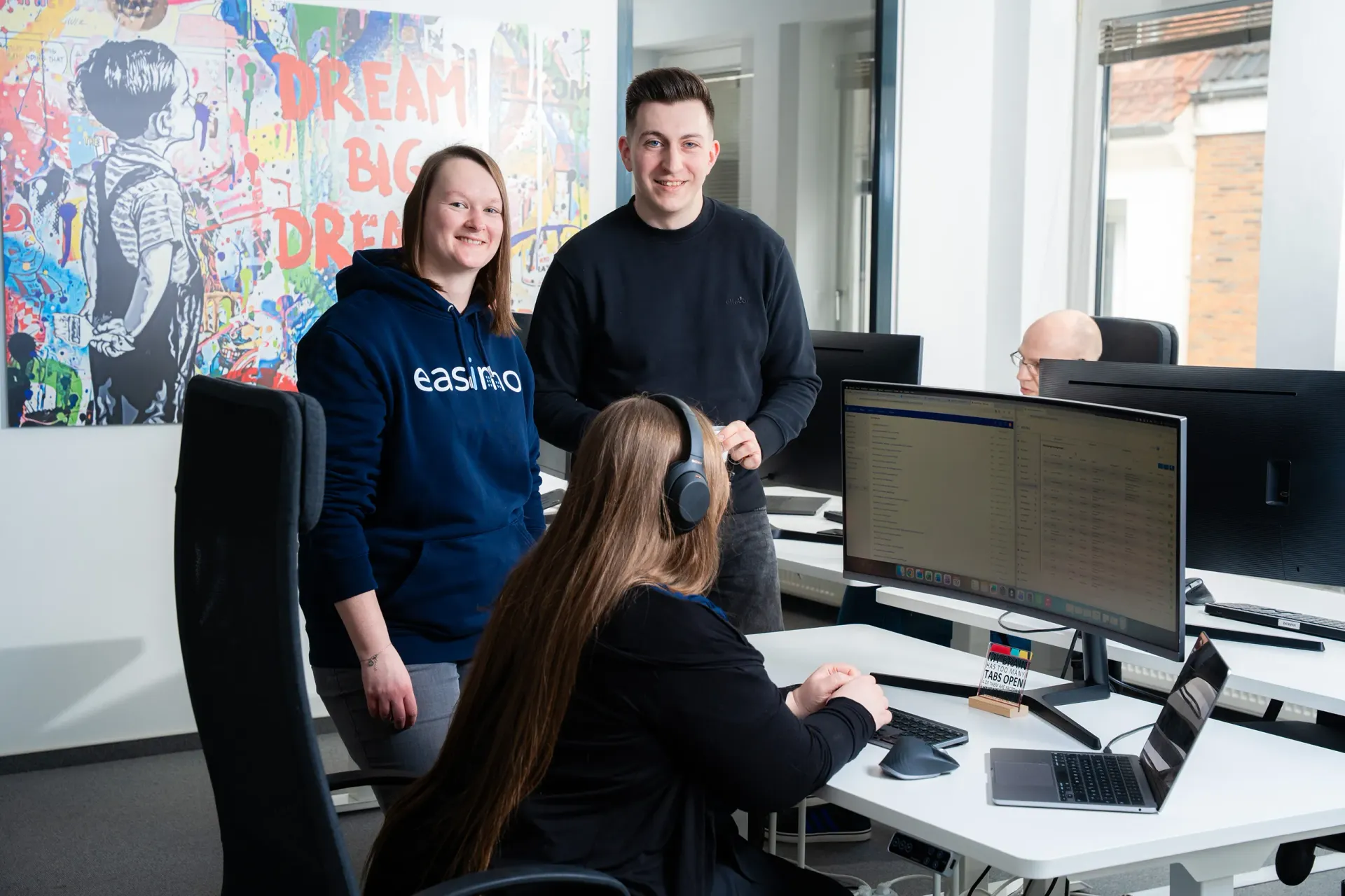 Support-Team von easimo im Büro: Mitarbeitende arbeiten gemeinsam an Monitoren und unterstützen Kunden der Immobilienverwaltungssoftware.